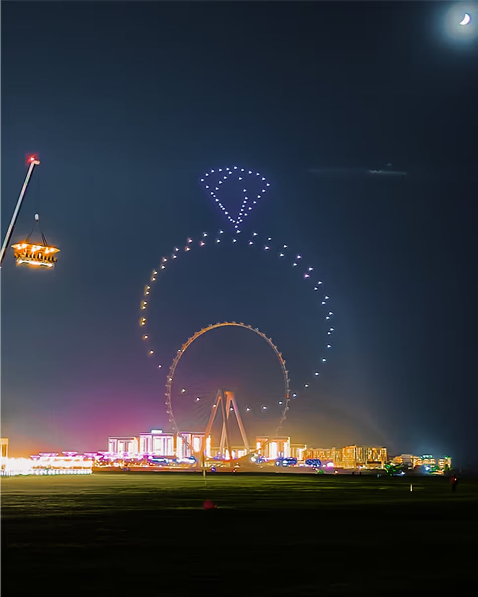 Drones drawing a diamond ring above Ain Dubai and Bluewaters at night