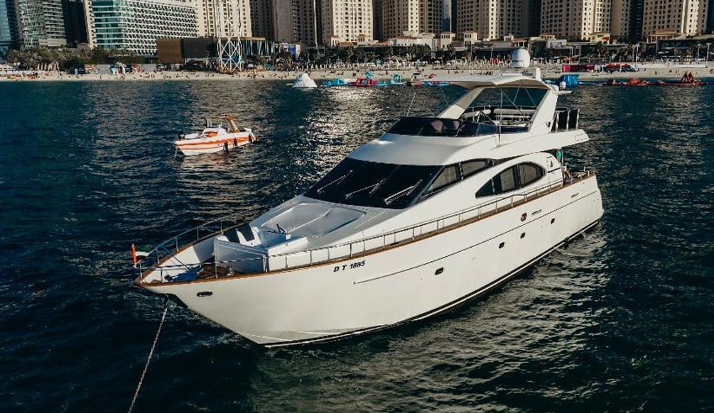 A large motor yacht anchored off the JBR beach at dusk