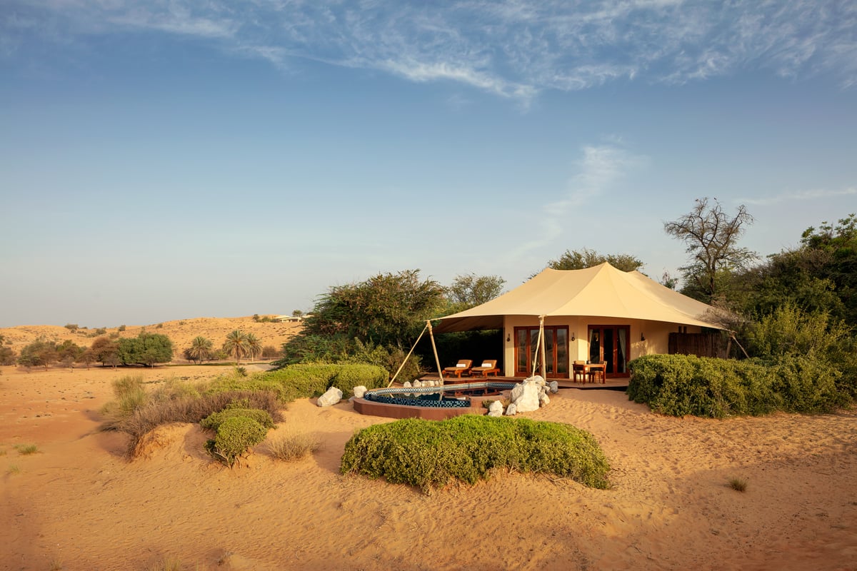 Bedouin Villa, tented pavilion with a private plunge pool among dunes and green shrubs, at Al Maha Desert Resort.
