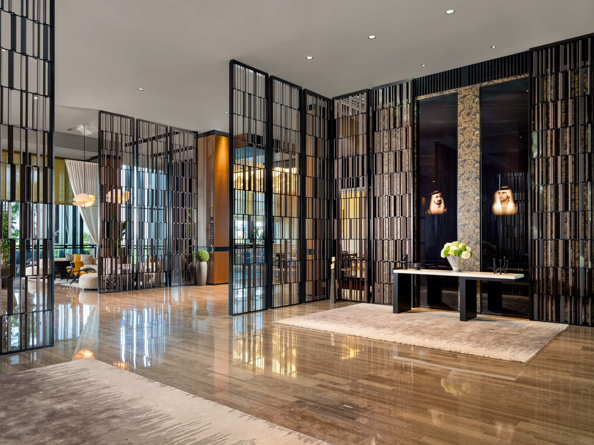 Banyan Tree Dubai's lobby, with tall metal screens, a console table with flowers and a polished marble floor.