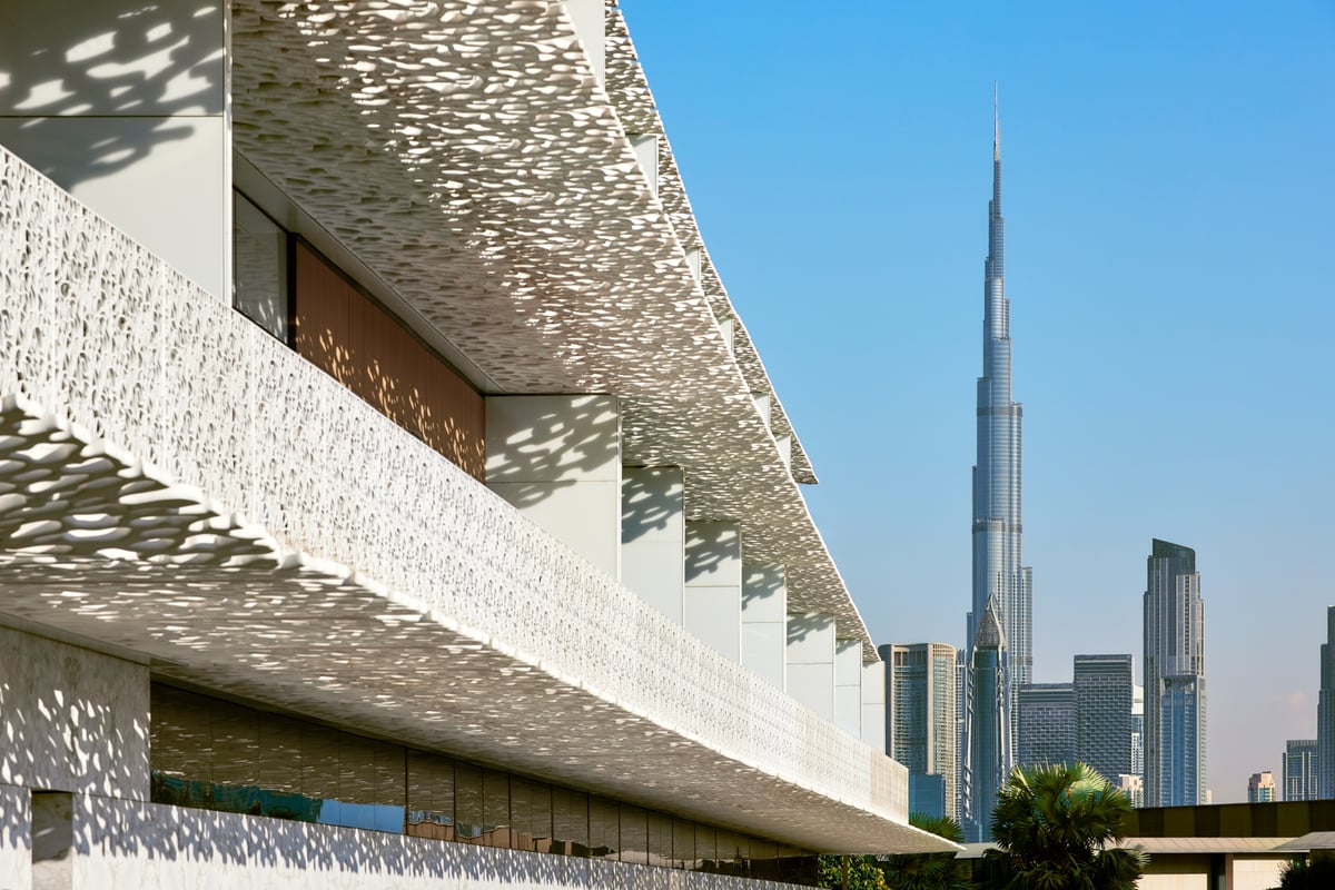 Pierced white balcony screens of the Bvlgari Resort Dubai with the Burj Khalifa and downtown towers rising beyond.