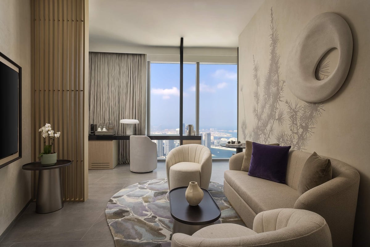 One Bedroom Suite, living room with curved sofa, armchairs and sculptural wall art, at Ciel Dubai Marina.