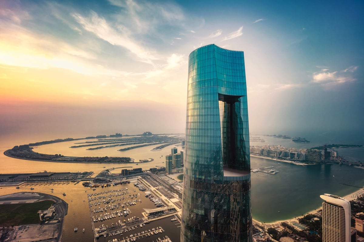 The glass tower of Ciel Dubai Marina seen from the air, with Palm Jumeirah and the marina harbor below.
