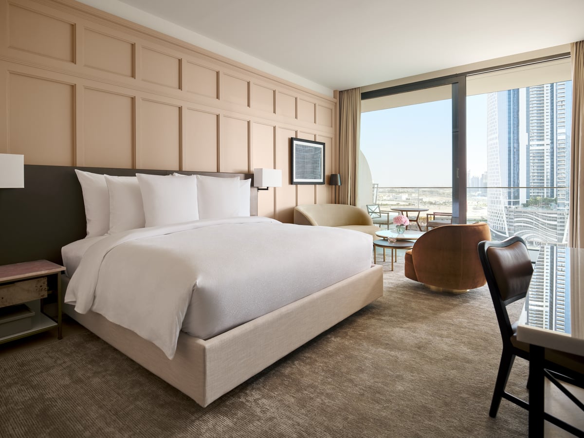 Sunrise Room, king bed, armchair and floor-to-ceiling windows overlooking the city, at The Lana.