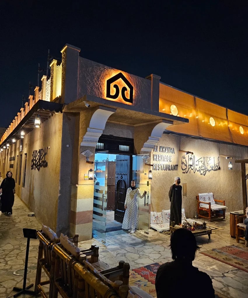 Al Khayma Heritage's lit entrance in the old Al Fahidi district at night, the restaurant's emblem above the door