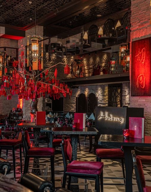 A blossom tree hung with red wishes over tables and red chairs in the dining room