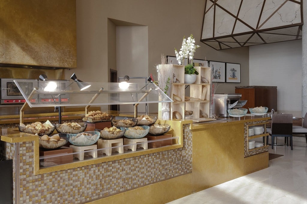 Breads and pastries under glass on a mosaic-fronted buffet counter