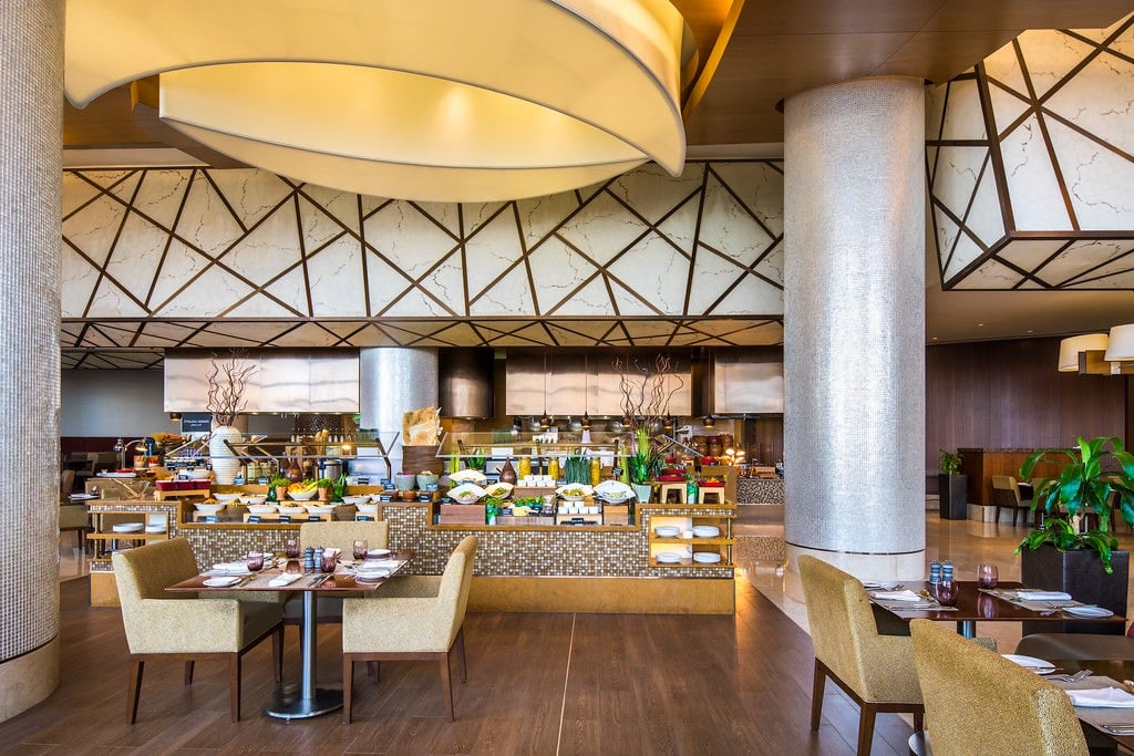 Laid tables with upholstered chairs in front of the buffet, a domed light above