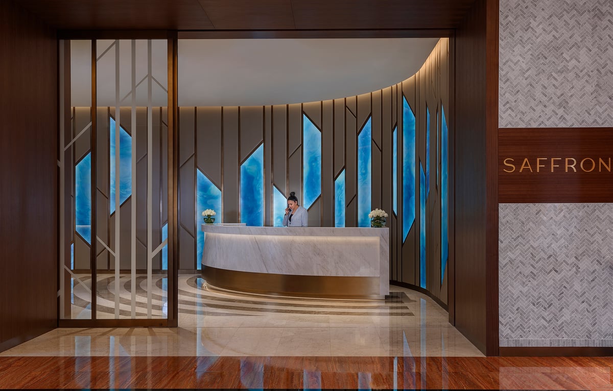 Saffron's reception desk in a curved marble lobby, the restaurant's name on the wall beside the doorway